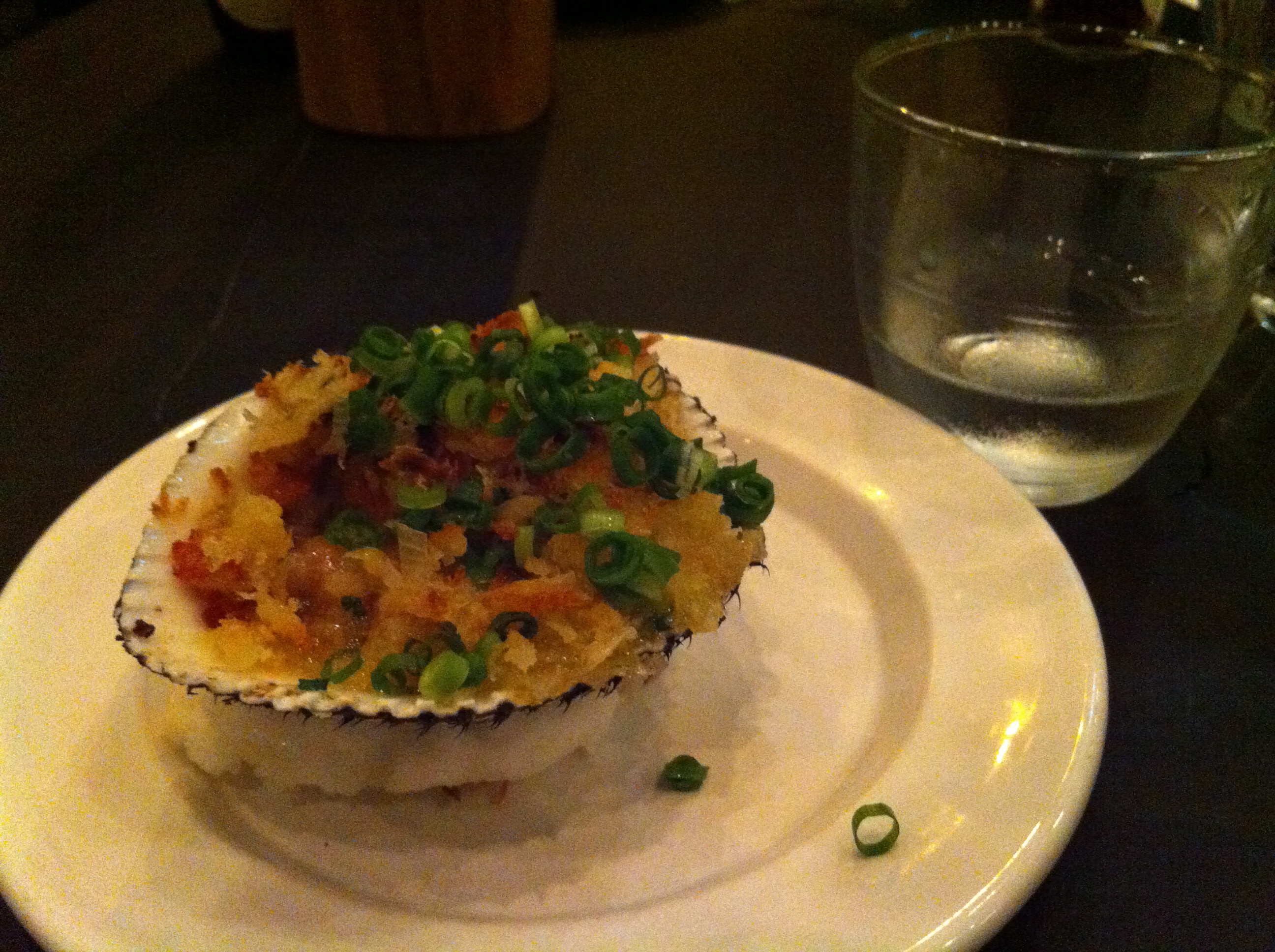 A bacon and panko-topped baked clam and a glass of the house namazake at Yardbird