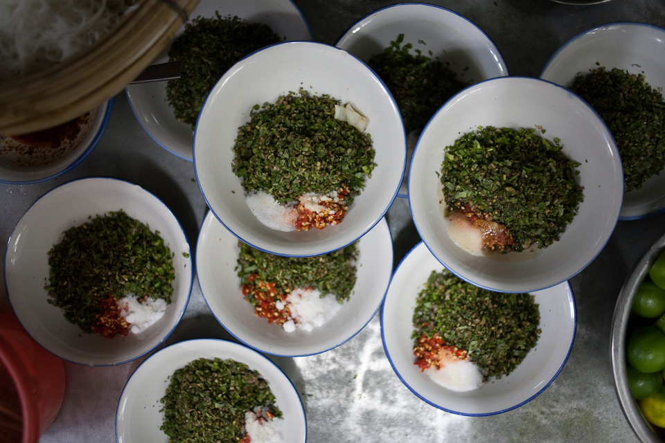 Bowls of herbs, chile, and salt, pre-prepared for noodle dipping sauce