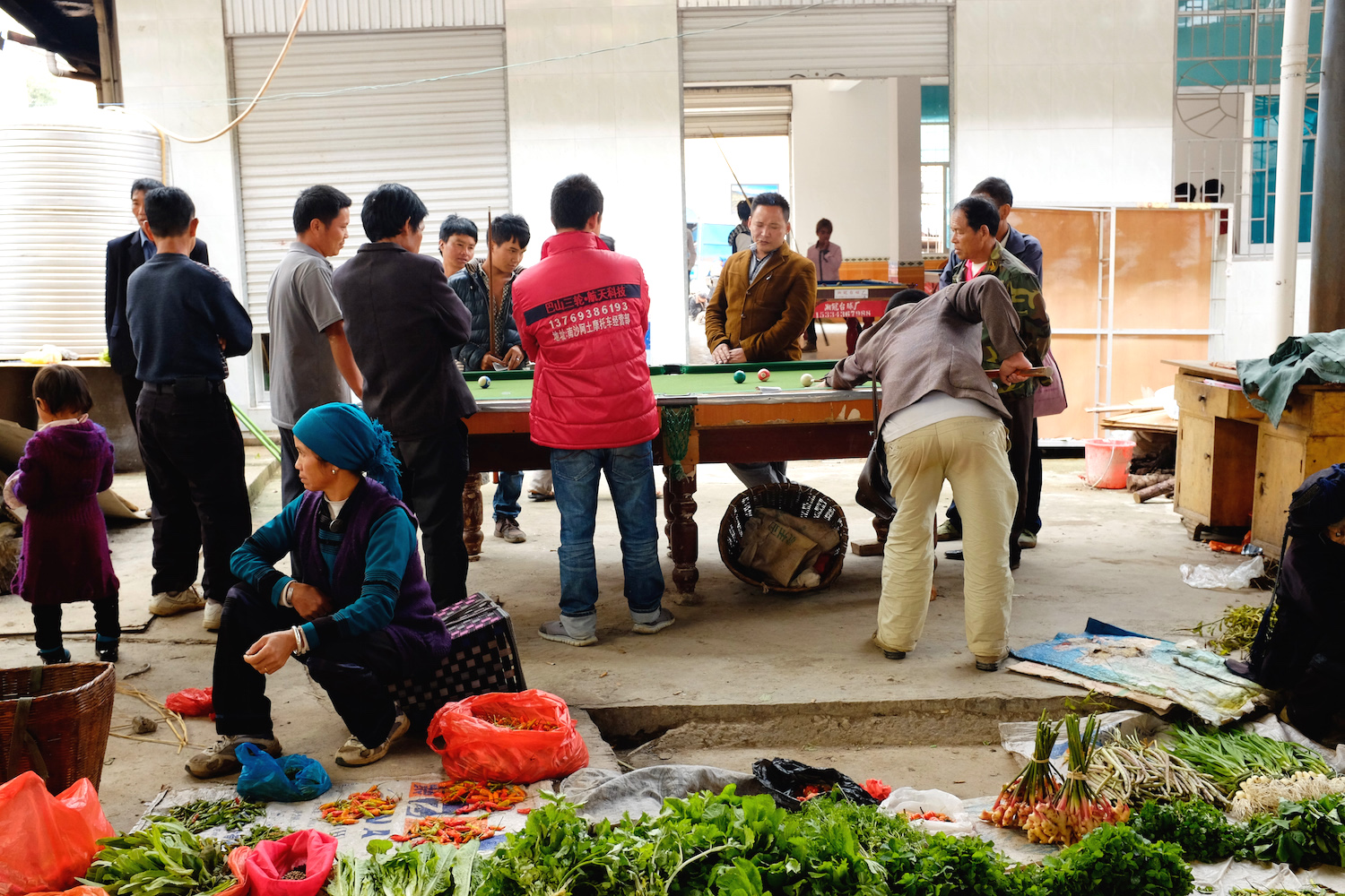 The men relax while the women sell vegetables